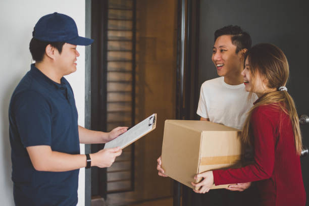istock Asian courier making a delivery to a smiling young couple 1219552269