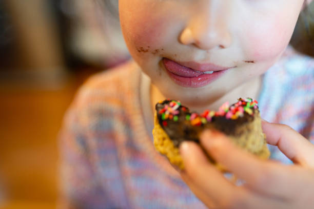 istock Kid eating colorful chocolate donuts 1219552353