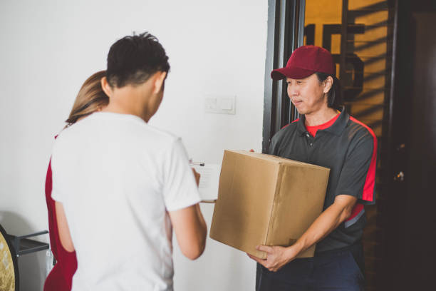 istock Asian courier making a delivery to a smiling young couple 1219552362