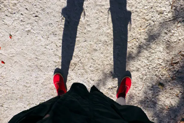 Photo of female photographer selfie with funny shadow, shade from torn jean at knee and red shoes