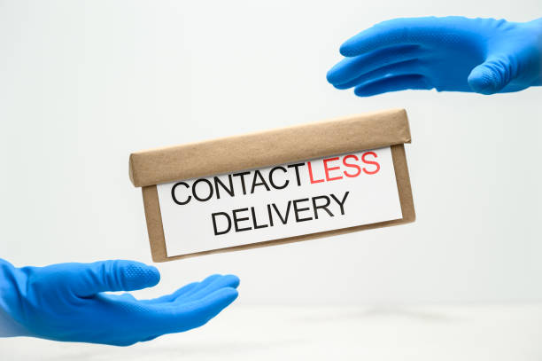 istock Contactless Safe Delivery Concept. A cardboard box levitates between hands in blue protective gloves on a light background. 1219552596