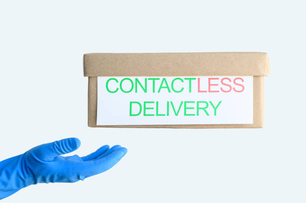 istock Contactless Safe Delivery Concept. A cardboard box levitates above a hand in a blue protective glove on a light background. 1219552604