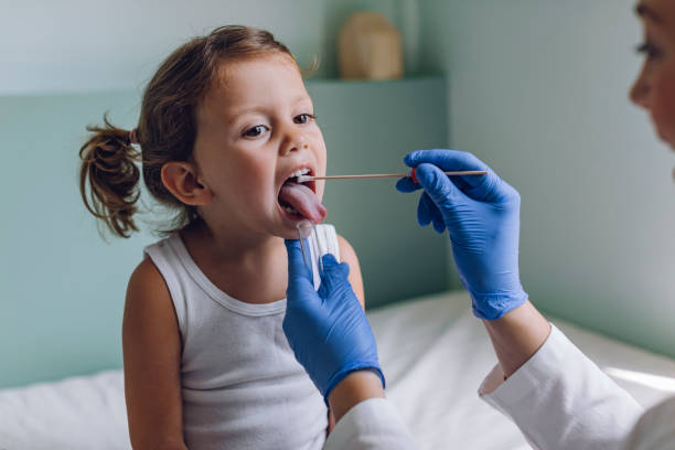 小女孩在醫院接受口腔拭子醫學檢查時 - 喉嚨 個照片及圖片檔