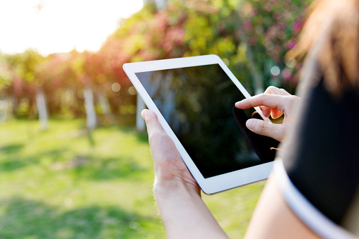 Woman hand using a digital tablet outdoors.