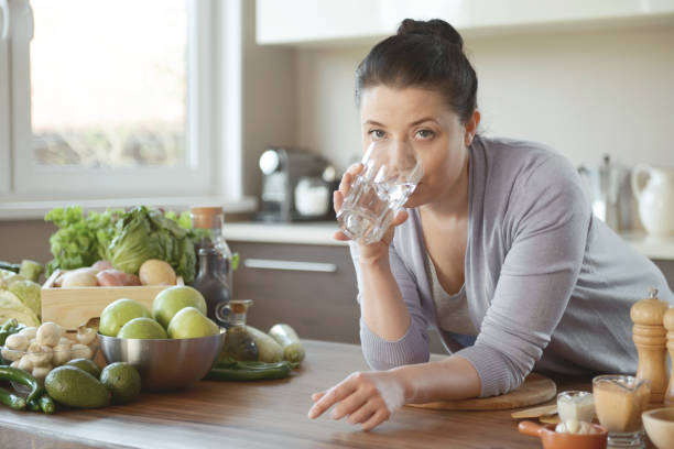 istock woman in the kitchen preparing food (drinking water) 1219556130