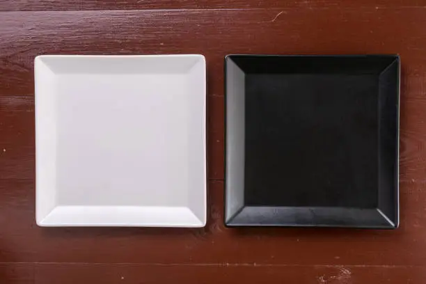 Flat lay above black and white square plates on the wooden boards table.