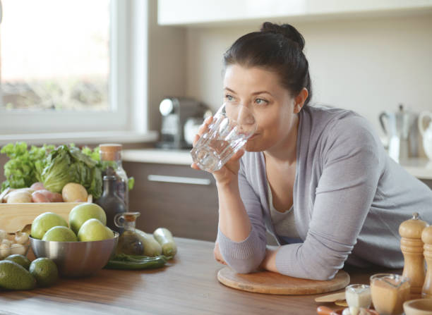 istock woman in the kitchen preparing food (drinking water) 1219557608