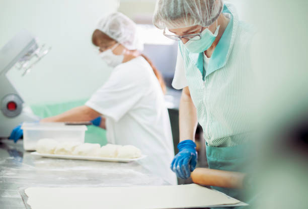 istock Women working in a bakery, wearing protective gloves and mask 1219559680