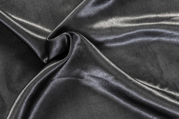 istock Delicate smooth soft black silk fabric background. Abstract crumpled satin texture. Glossy textile. 1219559925