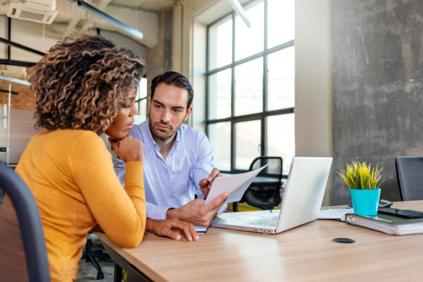 istock Serious businessman pointing at paperwork discussing corporate software with colleague 1219561084
