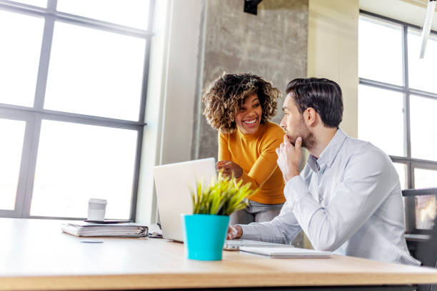 istock Two diverse smiling business people discussing online project 1219561086