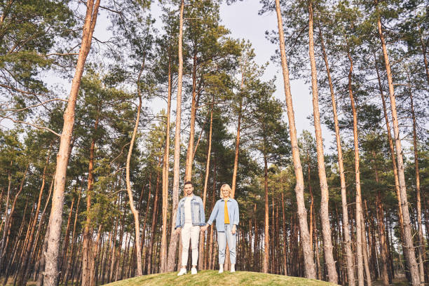 istock Young Caucasian couple standing among coniferous trees 1219561476