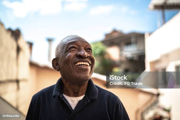 Portrait Of Senior Man Looking Up Dreaming At House Stock Photo - Download Image Now
