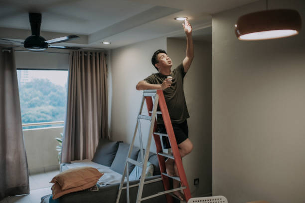 uma lâmpada asiática chinesa média adulto trocando lâmpada na sala de estar, casa apartamento - led lighting equipment light bulb installing - fotografias e filmes do acervo