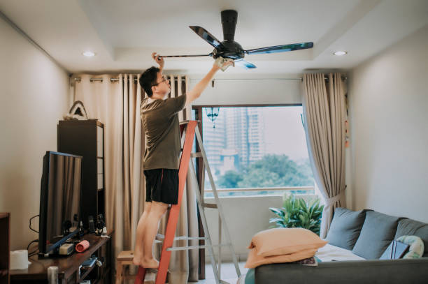 an asian chinese male cleaning ceiling fan at home an asian chinese male cleaning ceiling fan at home ceiling fan stock pictures, royalty-free photos & images