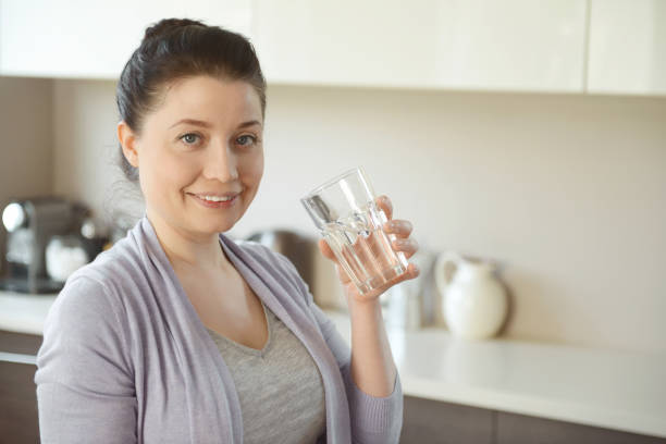 istock woman in the kitchen drinking water 1219562906