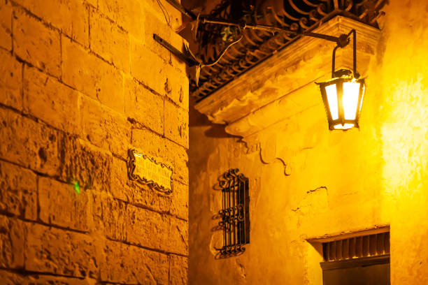 マルタの古代の首都、イムダの狭い通り。古代の町の照明付きの建物や壁の装飾の夜景。 - イムディーナ ストックフォトと画像