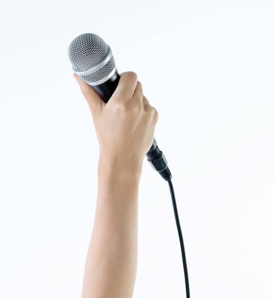 istock Woman hand holding a microphone on white background 1219563861