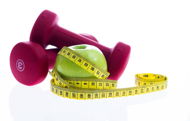 Green apple with a measuring tape and dumbbells.