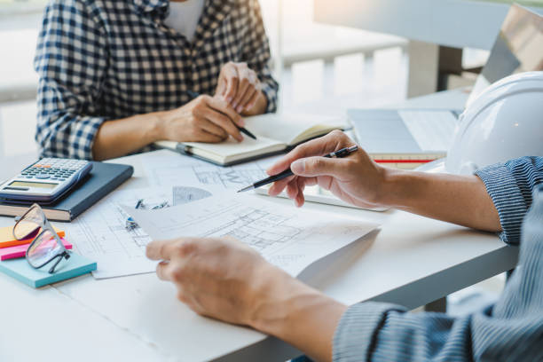 istock engineer Hand Drawing Plan On Blue Print with architect equipment discussing the floor plans over blueprint architectural plans at table in a modern office 1219564381