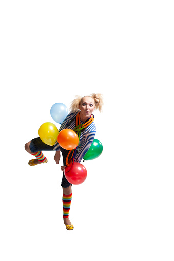 Girl clown with balloons has fun dancing, jumping, laughing, grimacing, cut out on a white background