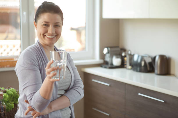 istock woman in the kitchen drinking water 1219569490