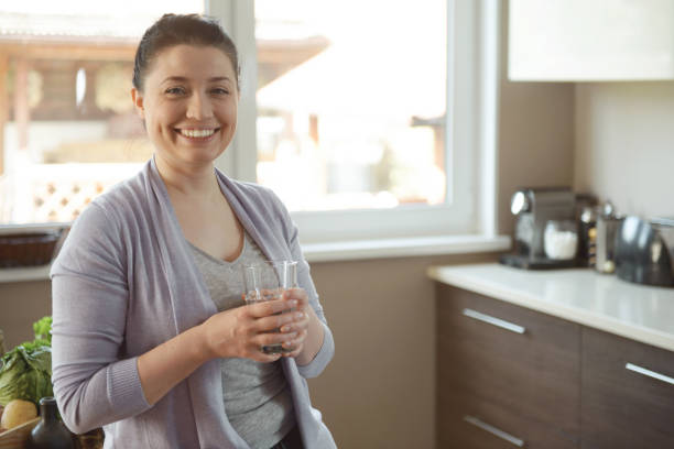 istock woman in the kitchen drinking water 1219569710