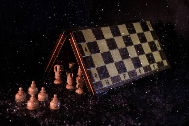 istock Main chess figures under the game board protecting themselves from the rain in front of the pawns under it, in a dark environment 1219569764