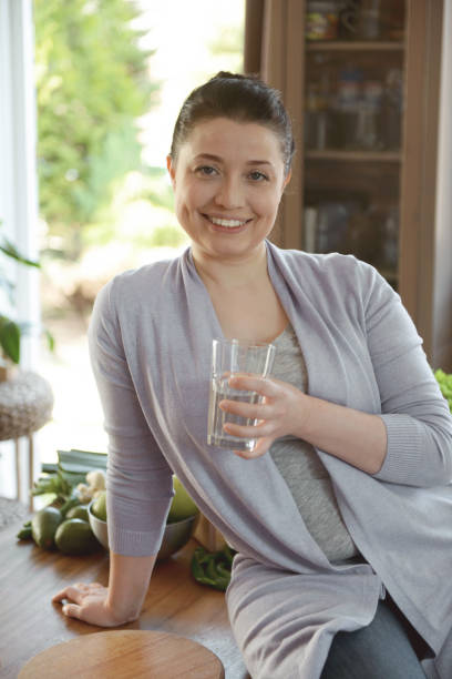 istock woman in the kitchen drinking water 1219569884