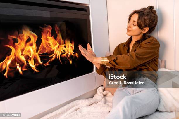 Woman Relaxing Near The Fireplace At Home Stock Photo - Download Image Now - Adult, Adults Only, Beauty