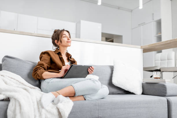 istock Woman with a tablet on the couch at home 1219569941