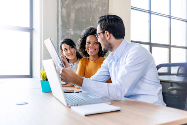 Male Caucasian mentor explaining females intern online task.