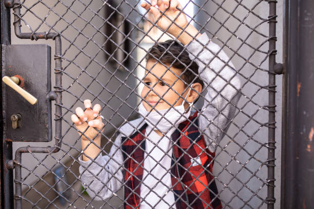 istock A boy looking through a wire gate stock photo 1219573957
