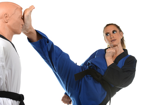 Martial artist kicking a training mannequin in the head.