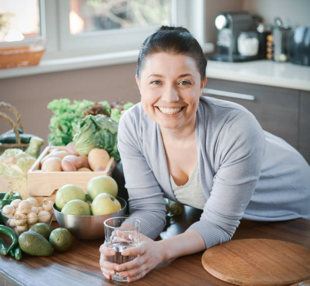 istock woman in the kitchen preparing food (drinking water) 1219575920