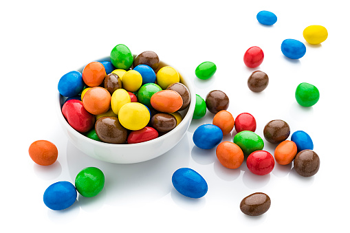 High angle view of multi colored chocolate candies in a bowl isolated on white background. High resolution 42Mp studio digital capture taken with SONY A7rII and Zeiss Batis 40mm F2.0 CF lens