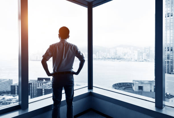 istock Businessman looking at city through office window 1219578767