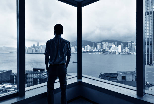 istock Businessman looking at city through office window 1219578772
