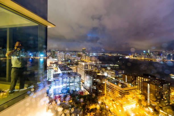 Businessman standing by the window and using phone at night.