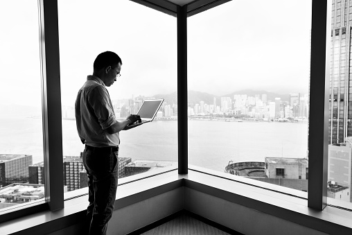 Businessman standing by the window and using laptop.