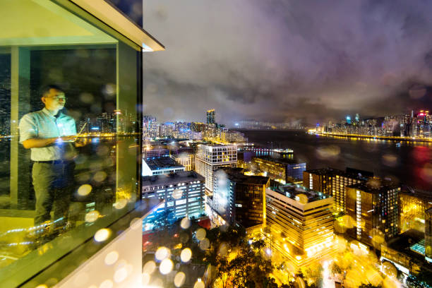 Businessman standing by the window and using laptop at night.