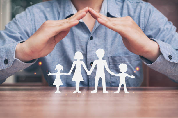 istock Protecting hands over paper family. 1219580315