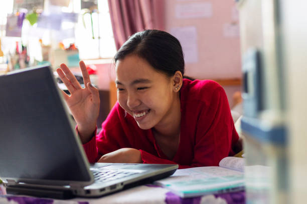 Young girl uses her laptop teleconferencing in the house Asian teenage girl having video call with teacher for home schooling using laptop assistive technology stock pictures, royalty-free photos & images