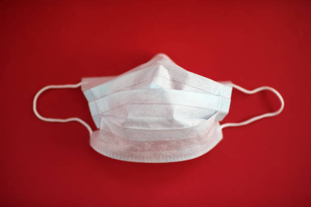 istock BLUE PROTECTIVE MEDICAL MASK ON RED BACKGROUND 1219585281