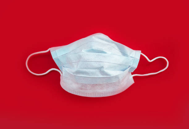 istock BLUE PROTECTIVE MEDICAL MASK ON RED BACKGROUND 1219585282