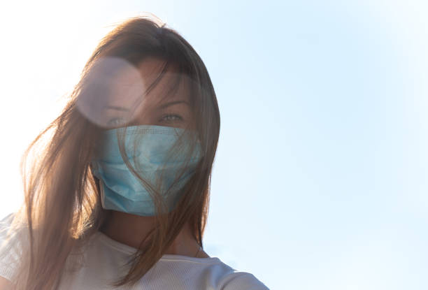 istock Young woman with medical face mask outdoors, copy space. 1219591335