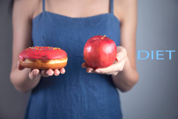 istock woman hand holding Donut and apple 1219591366