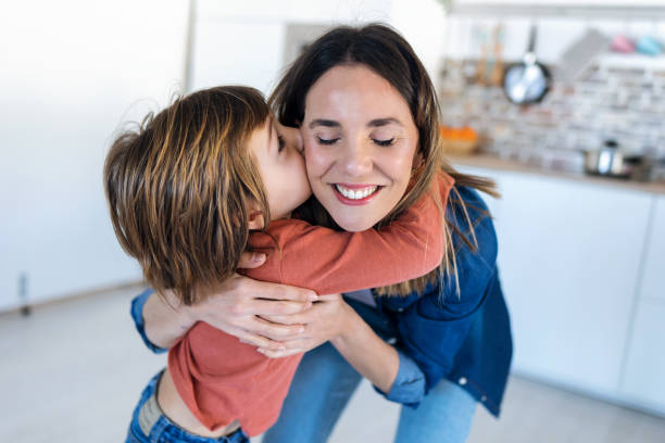 istock Nice boy kissing his mother while standing in the kitchen at home. 1219591402