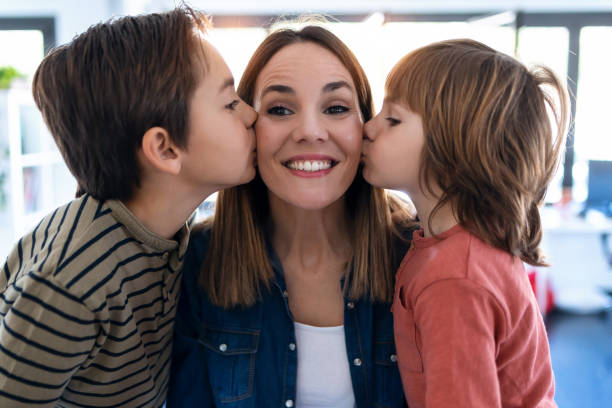 Nice brothers kissing his mother while standing at home.