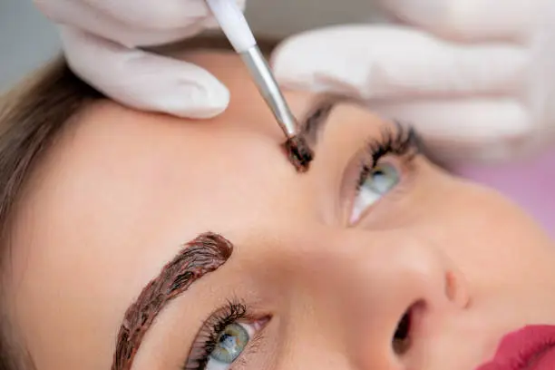 Close-up Photo of Beautician Applying Dye on Woman's Eyebrows